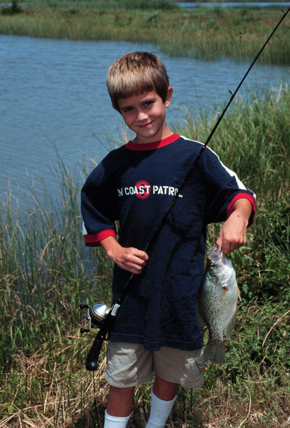 A young boy shows off his latest catch