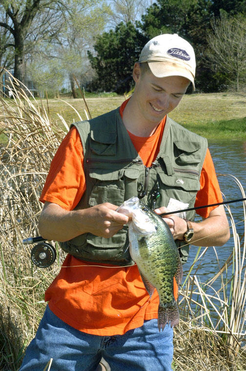 A young angler holds a crappie