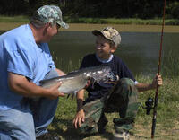 A young angler checks out his large catch: a catfish!